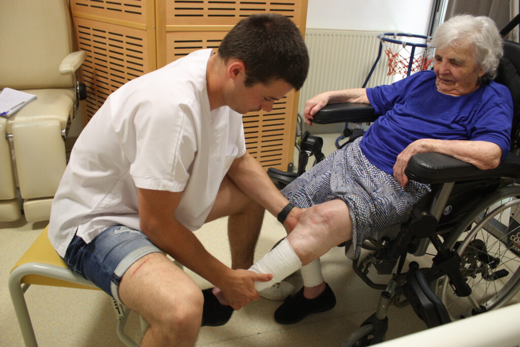 Dans la salle de rééducation, Tanguy le kinésithérapeute poursuit ses manipulations avec les jambes de Georgette © Récit en Série - Isabelle Desprez.
