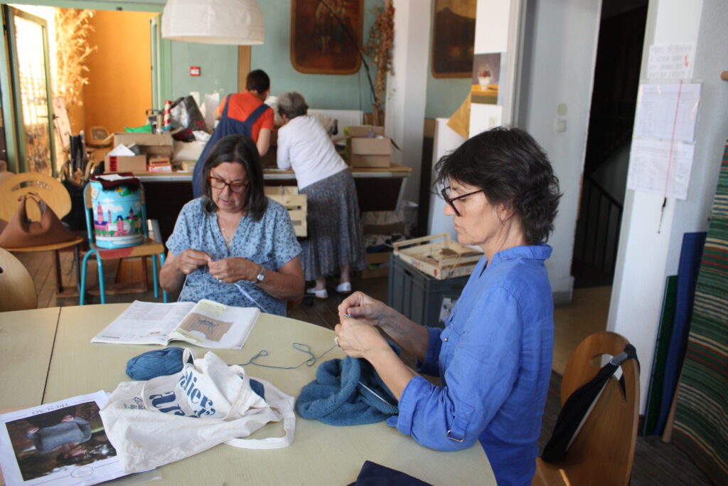 Cathy et ?? ne lâchent pas leur tricot tandis que Rosine et Pascale cherchent des trésors dans les dons à l'atelier couture © Récit en Série - Isabelle Desprez.  