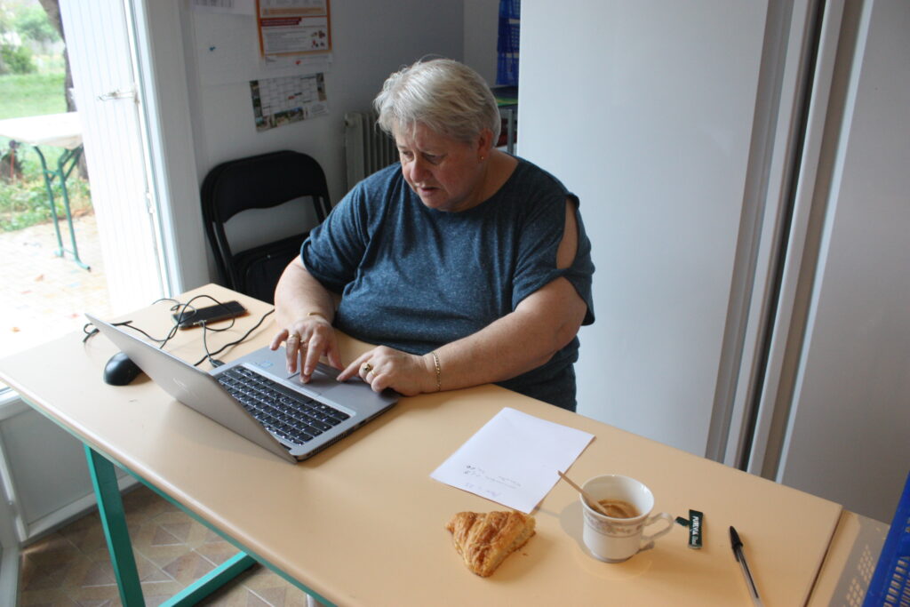 Sylviane, l'une des trois co-responsables de l'antenne L'Isloise des Restos du Cœur, finit de comptabiliser les stocks dans le logiciel avant la distribution des menus aux personnes accueillies © Récit en Série - Isabelle Desprez.